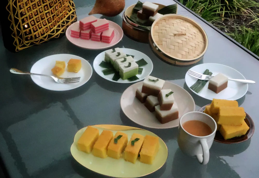 Assorted desserts on plates with a cup of tea on a reflective surface.