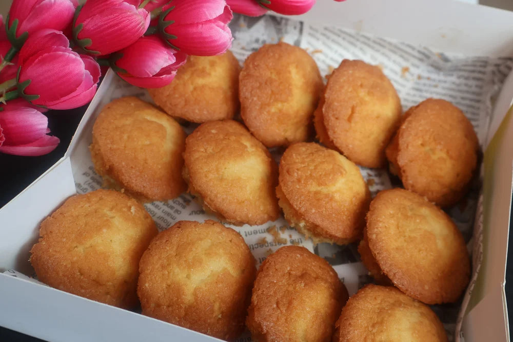 Box of fried dough balls with pink flowers in the background