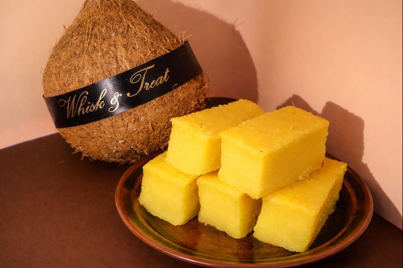 Coconut and yellow blocks on a plate with 'Whisk & Treat' branding.